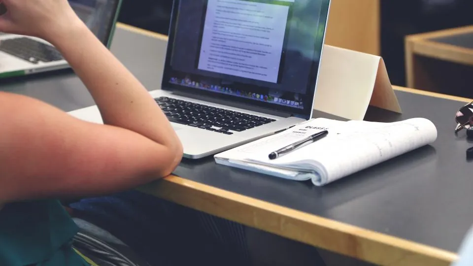 GCSE student revising with a laptop and notebook